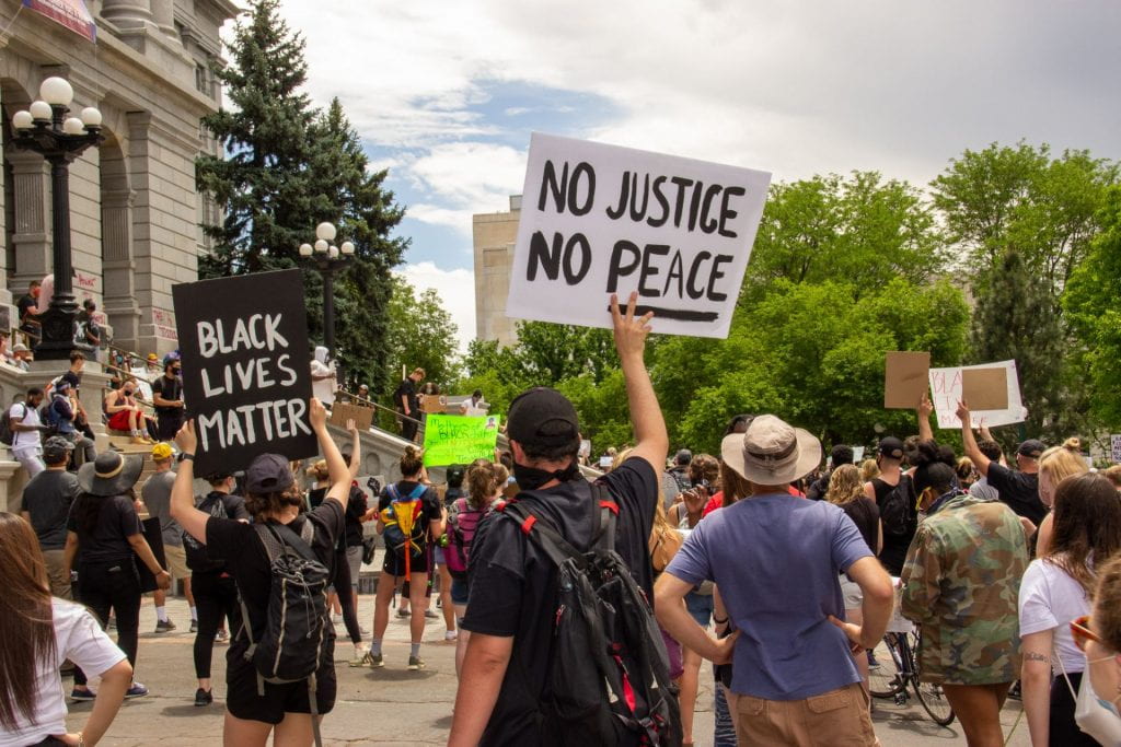 Protesters holding signs saying No Justice, No Peace, and Black Lives Matter