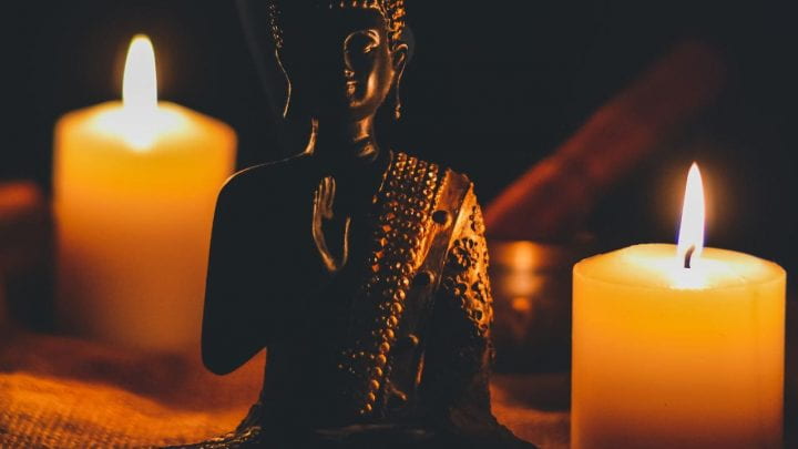 Seated Buddha statue surrounded by candles